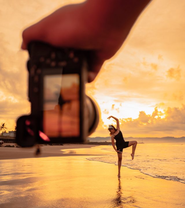A camera photographs an Asian woman doing a ballet dance lonely on the beach A camera photographs an Asian woman doing a ballet dance lonely on the beach during the sunrise